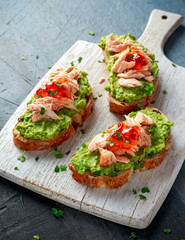 Homemade Toast sandwich with Salmon, Avocado and chilli jam on wihte wooden board. healthy food