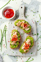 Homemade Toast sandwich with Salmon, Avocado and chilli jam on wihte wooden board. healthy food