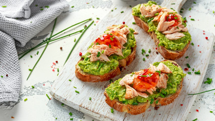 Homemade Toast sandwich with Salmon, Avocado and chilli jam on wihte wooden board. healthy food