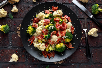 Steamed Broccoli, Cauliflower Salad with Bacon, parmesan cheese in a black plate. healthy food concept