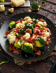 Steamed Broccoli, Cauliflower Salad with Bacon, parmesan cheese in a black plate. healthy food concept