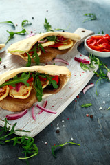 Stuffed mushroom and halloumi pittas with red pepper and onion in a white board.