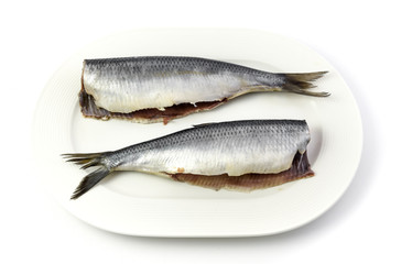 Salted herrings without head on the plate, isolated on white background.