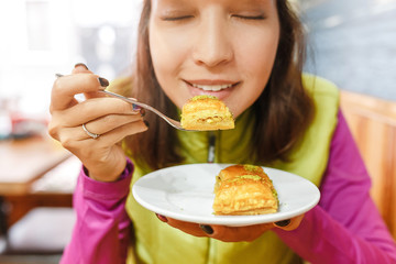Woman eating Turkish baklava dessert in cafe