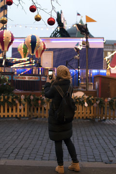 the girl at the Christmas market takes a picture of the carousel on the phone