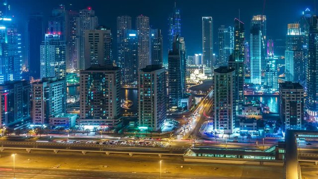 Colourful skyline of Dubai Marina by night. Scenic elevated view over the creek with skyscrapers and highways. 4K time lapse. Scenic travel and architectural background. 