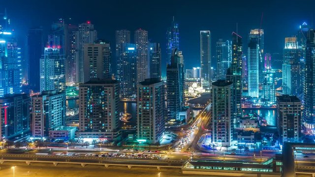 Colourful skyline of Dubai Marina by night. Scenic elevated view over the creek with skyscrapers and highways. 4K time lapse. Scenic travel and architectural background. 