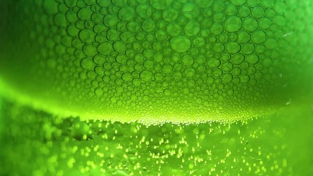 Bubbles in green glass of beer close up macro.
