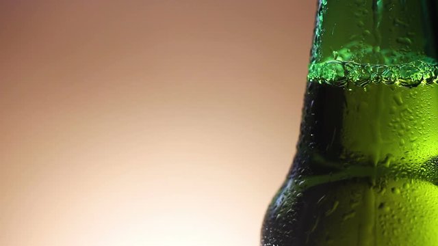 Drop of condensate drains on a green bottle of beer.