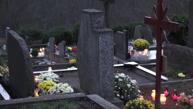 Rural cemetery tomb stones and candles burn at evening near forest. 4K