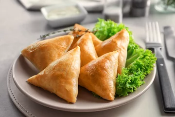 Poster Plate with delicious baked samosas on table © Africa Studio