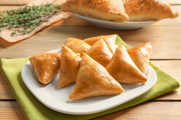 Plate with delicious baked samosas on table