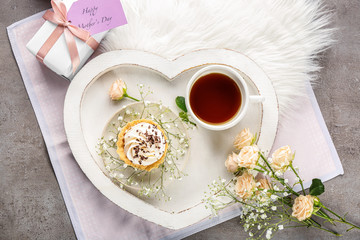 Tray with breakfast, flowers and gift box on grey background. Mother's day composition