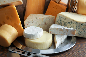 Plate with different kinds of delicious cheese on table, closeup