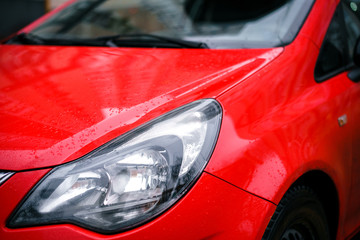 headlight on the front of the red car after the rain.