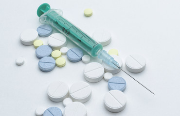 colorful tablet and disposable syringe on white background, closeup