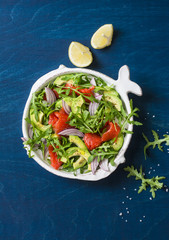 Smoked salmon, avocado, arugula, red onion salad. Healthy snacking on blue background, top view