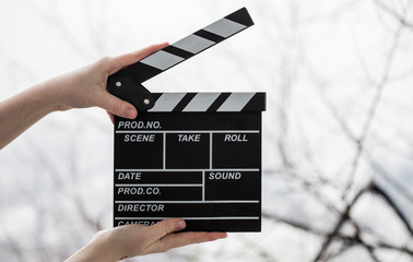 Female hands holding movie clapper isolated on white
