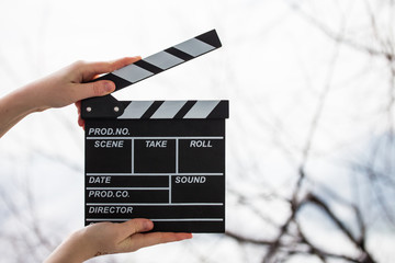 Female hands holding movie clapper isolated on white
