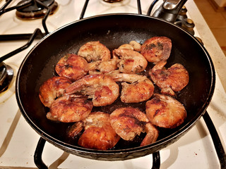 Giant tiger shrimps fried in oil in a frying pan on a gas stove
