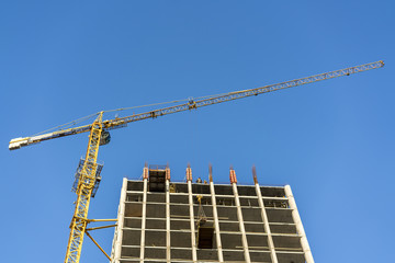 Construction of a high-rise building. Crane, builders against the blue sky