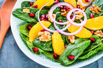 Spinach salad with orange pomegranate and nuts.Light healthy vitamin salad bowl.
