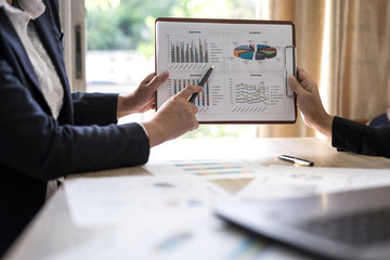 financial Image of two young business people pointing at business document during discussion at meeting , Notebook on wood table