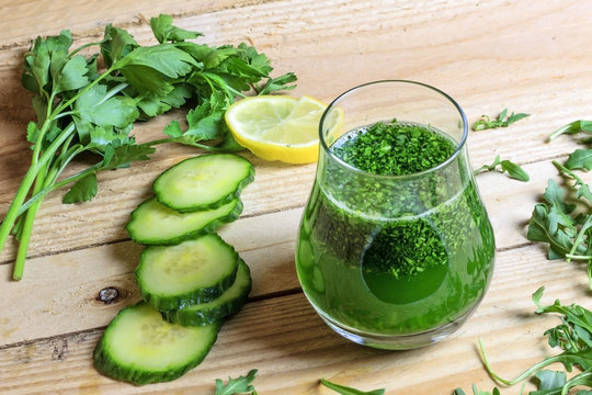 Healthy green juice with parsley and cucumber on wooden background