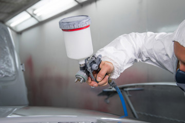 Painter spray gun in the hands of a painter.