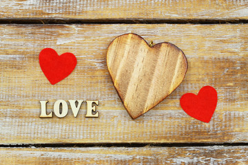 Word love written with wooden letters and hearts on rustic surface
