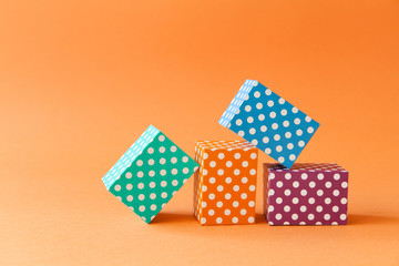 Abstract colorful geometric background vivid polka dots pattern cube boxes. Violet blue green rectangular block composition on orange paper background. Shallow depth of field