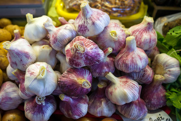 close up of white and purple garlic bulbs on market stand for sale