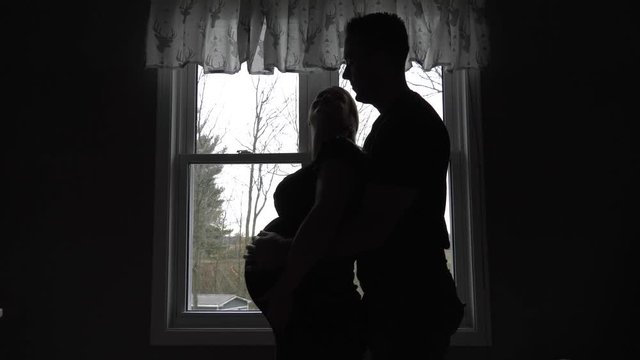 pregnant woman looks up at her man behind her rubbing her belly 4k