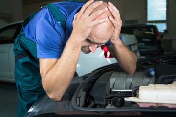 Young car service technician who repair the car engine motor.