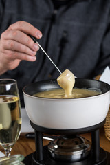 Mann dippt Brot in Schweizer Käsefondue