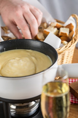 Mann isst Brot bei K&auml;sefondue mit Fonduegabel 