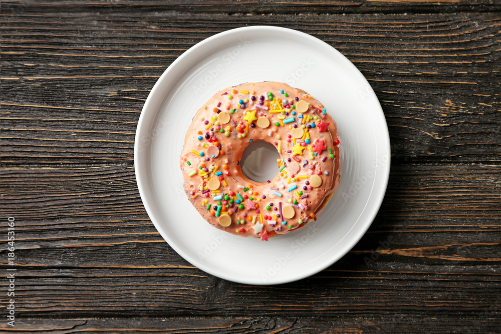 Wall mural Plate with tasty donut on wooden table