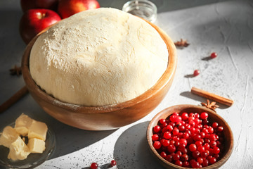 Bowl with fresh raw dough and cranberries on table
