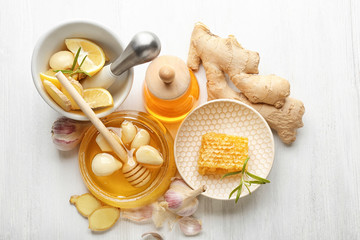 Composition with honey and garlic as natural cold remedies on white wooden background, top view