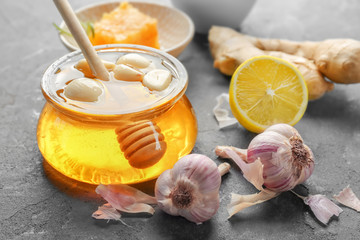 Glass jar with honey and garlic on table