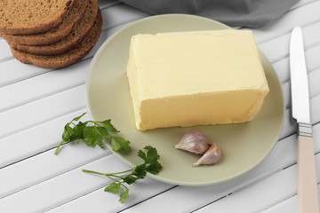 Plate with tasty fresh butter on wooden table