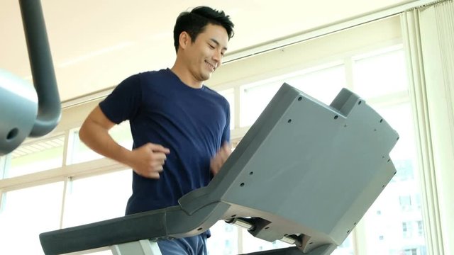 Close-up footage of asian man male running on treadmill in sport gym. Shot on in 4K (UHD).  