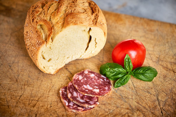 Pane siciliano, salame affettato, pomodoro e basilico su tagliere