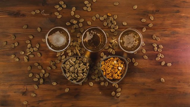 Beer in glass with pistachios on a wooden table. Beer, crackers and almond macadamia peanut cashew nut on the wooden background. Beer background top view.