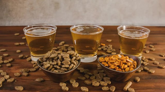 Beer in glass with pistachios on a wooden table. Beer, crackers and almond macadamia peanut cashew nut on the wooden background. Beer tasting. 