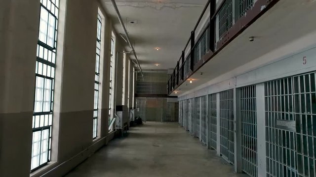 Hallway with prison cells on one side and windows to the outside on the other