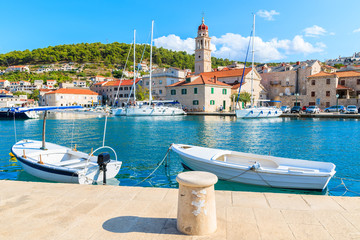 Fototapeta premium Fishing boats in Pucisca port with beautiful church in background, Brac island, Croatia