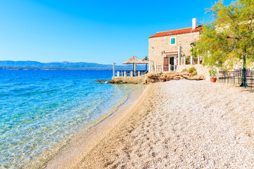Beautiful beach and small coastal restaurant in Bol town, Brac island, Croatia - obrazy, fototapety, plakaty