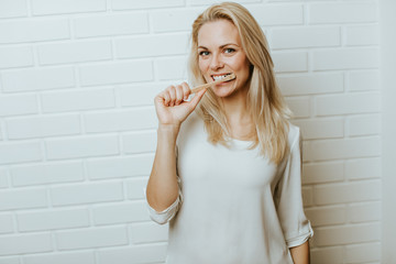 Beautiful blond  caucasian woman posing in front of a white brick backround and  having fun