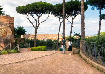 Couple walking on scenic Palatine Hill overlooking the Colosseum in Rome, Italy